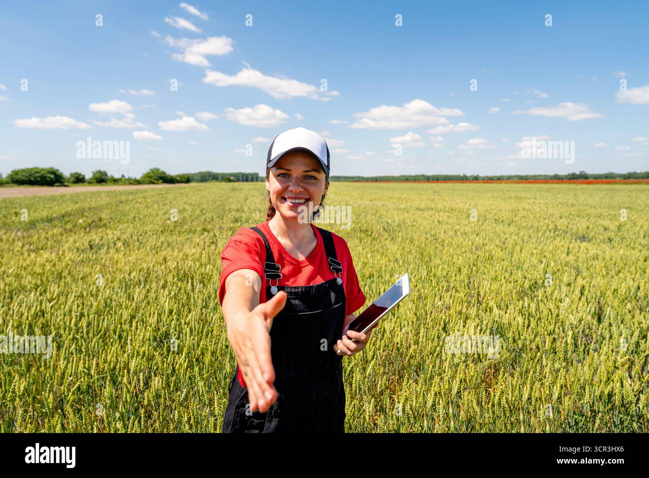 Agricoltore con tablet digitale nel campo del grano che si avvicina per una stretta di mano Foto Stock