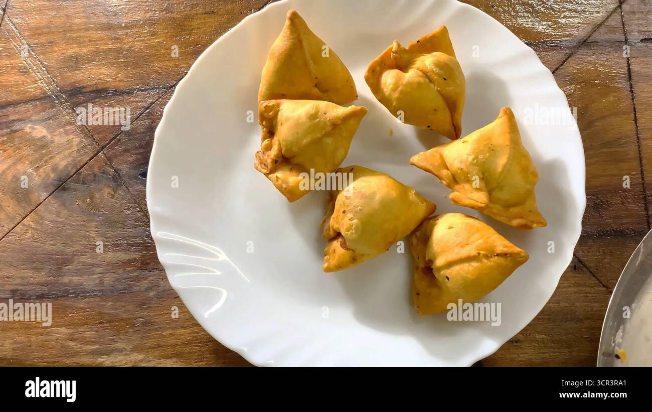 Samosa - Samosa è un popolare cibo indiano e uno spuntino della cucina indiana preparato con pasta croccante, ripieno di patate speziate e piselli. Cibo da strada iconico Foto Stock