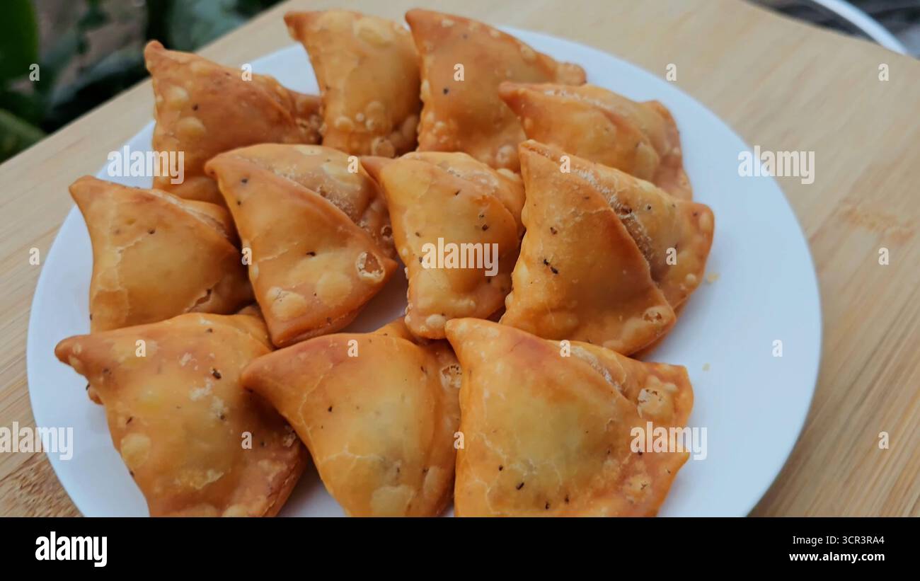 Samosa - Samosa è un popolare cibo indiano e uno spuntino della cucina indiana preparato con pasta croccante, ripieno di patate speziate e piselli. Cibo da strada iconico Foto Stock