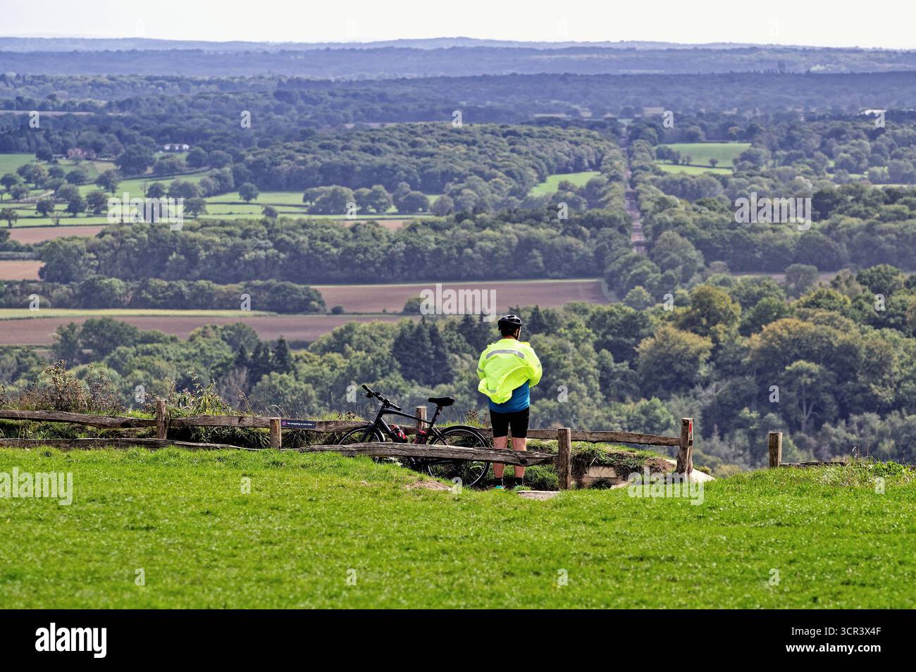 Un ciclista solitario che si gode la vista dalla cima di Box Hill Dorking Surrey Inghilterra Regno Unito Foto Stock