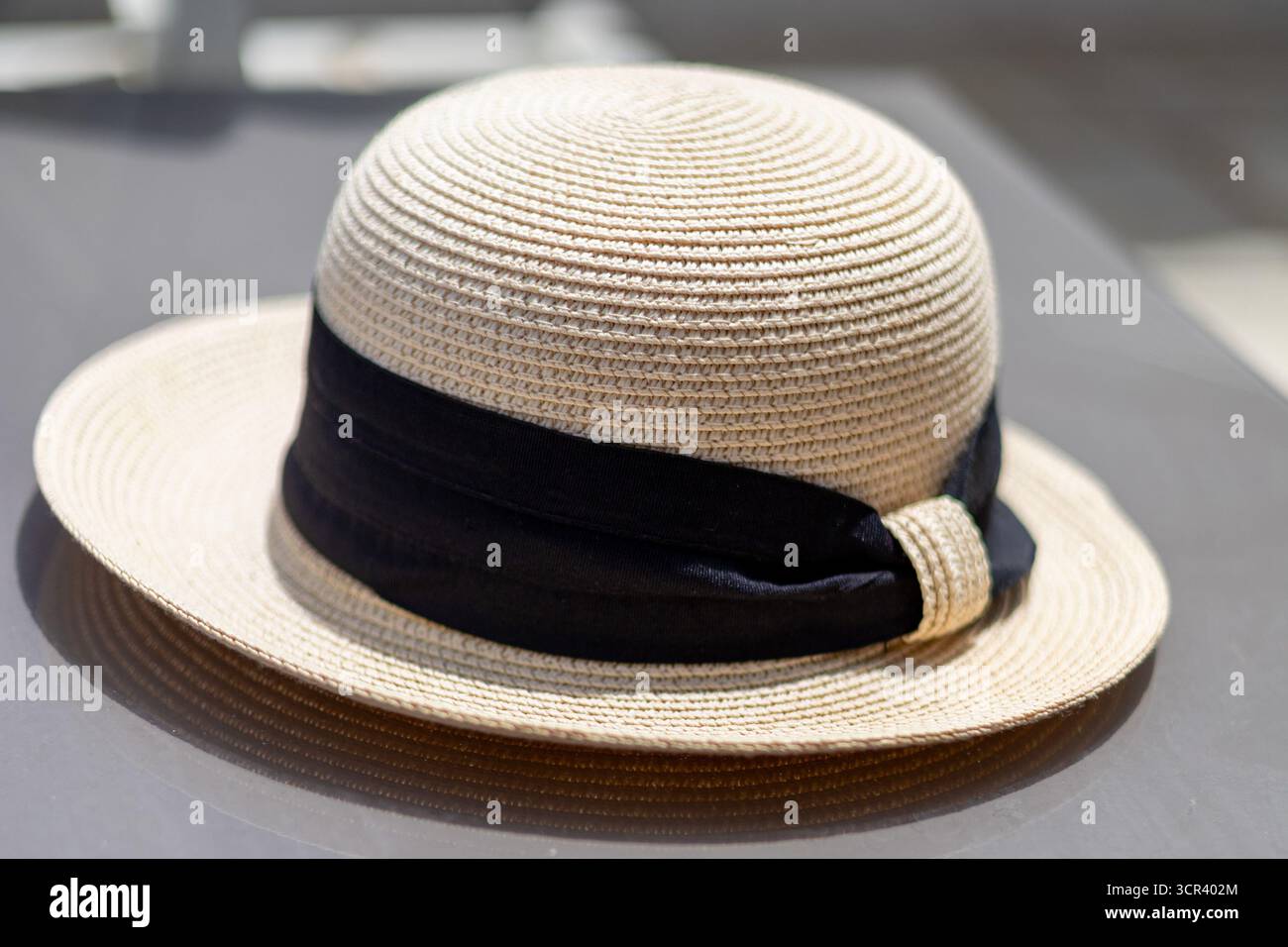 Cappello di paglia con nastro nero su sfondo grigio Foto Stock