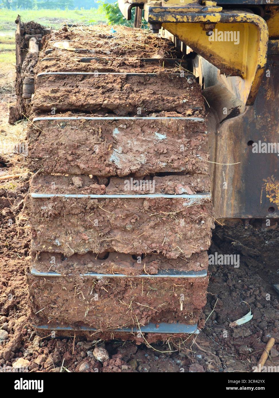 Un primo piano della pista di un bulldozer ricoperta da spessi strati di fango e suolo Foto Stock