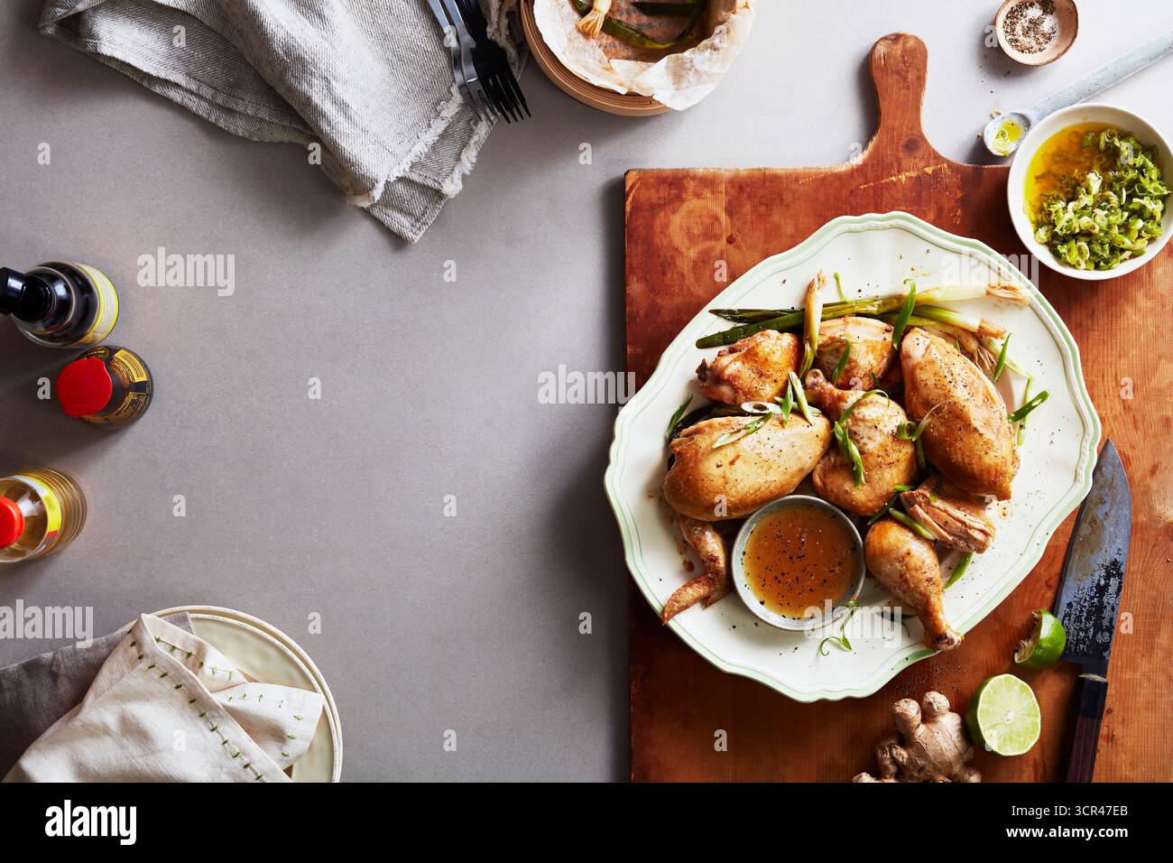 Quaglie arrostite su piatto con salsa, guarnite con erbe e lime, adagiate su tavola di legno. Foto Stock