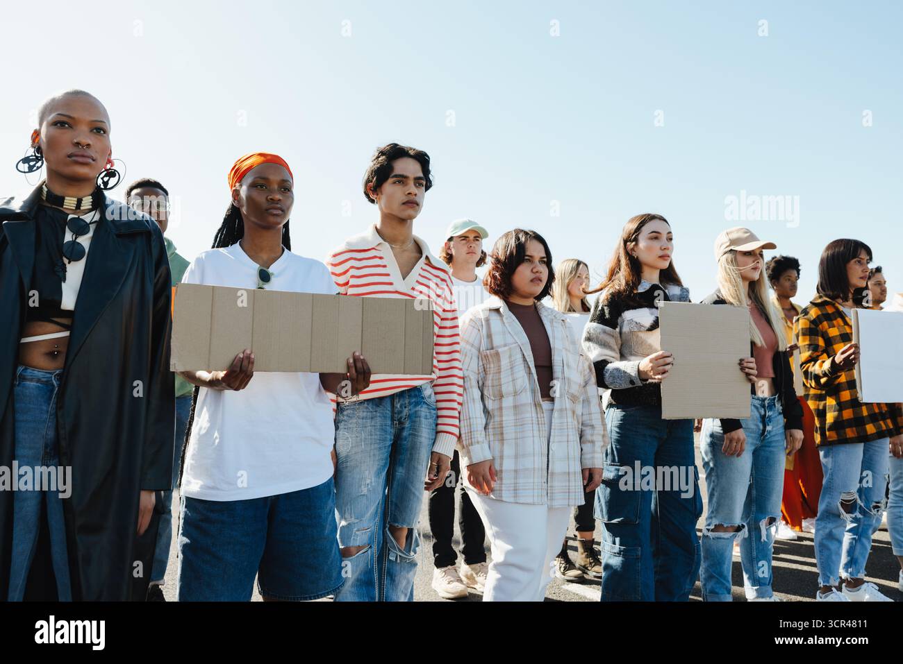 Un gruppo di giovani adulti diversi in piedi insieme a dei cartelli durante una pacifica manifestazione all'aperto, che ritrae l'unità e l'empowerment. Foto Stock Un gruppo di giovani adulti diversi in piedi insieme a dei cartelli durante una pacifica manifestazione all'aperto, che ritrae l'unità e l'empowerment. Foto Stock