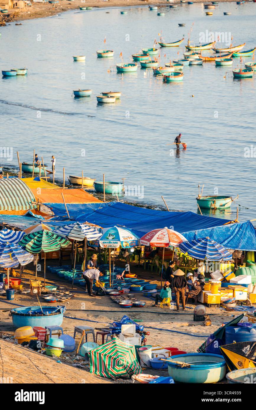Vivace mercato sul mare con barche colorate e teloni vicino alle acque calme. MUI ne, Vietnam Foto Stock