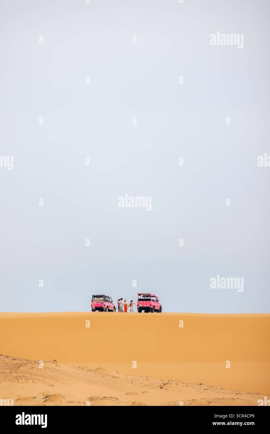 Veicoli fuoristrada rosa e persone su vaste dune di sabbia desertica sotto il cielo limpido. Phuoc Dinh, Ninh Thuan, Vietnam Foto Stock