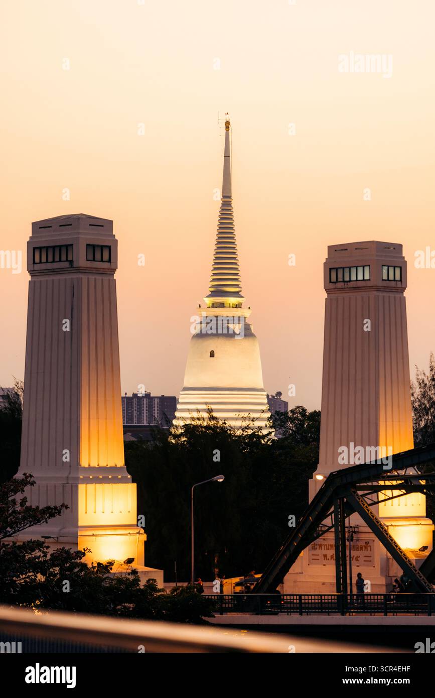 Torri illuminate e una guglia del tempio al tramonto in un paesaggio urbano. Bangkok, Thailandia Foto Stock