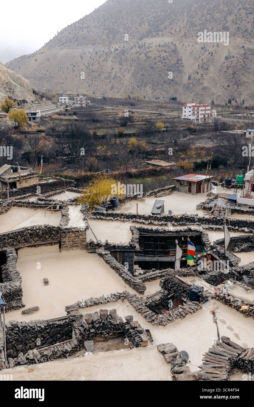 Case in pietra in un villaggio montano con sentieri terrazzati e colline lontane. Marpha, Annapurna, distretto di Mustang della provincia di Gandaki, Nepal Foto Stock