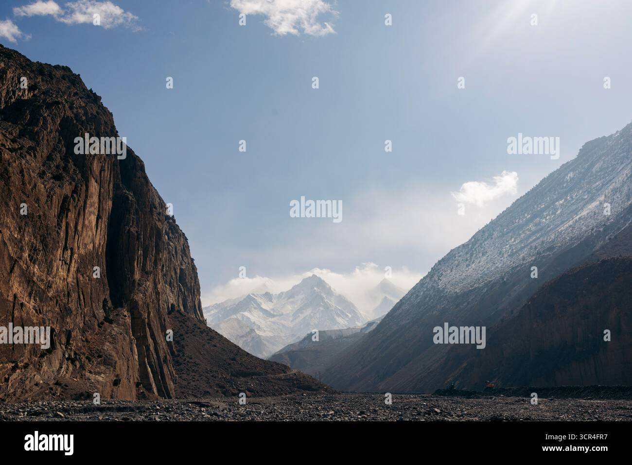 Montagne maestose sotto cieli azzurri e scogliere frastagliate che incorniciano una lontana vetta innevata. Strada F042, Annapurna, distretto di Mustang, provincia di Gandaki, Nepal Foto Stock