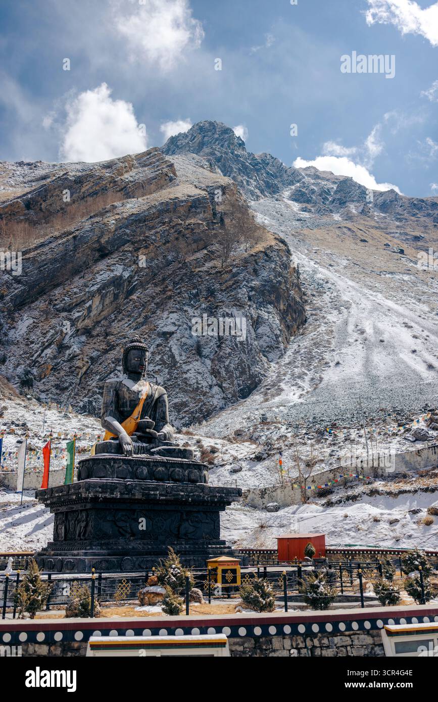 Maestoso paesaggio montano con grande statua seduto e colorate bandiere di preghiera. Muktinath, Annapurna, distretto di Mustang, provincia di Gandaki, Nepal Foto Stock