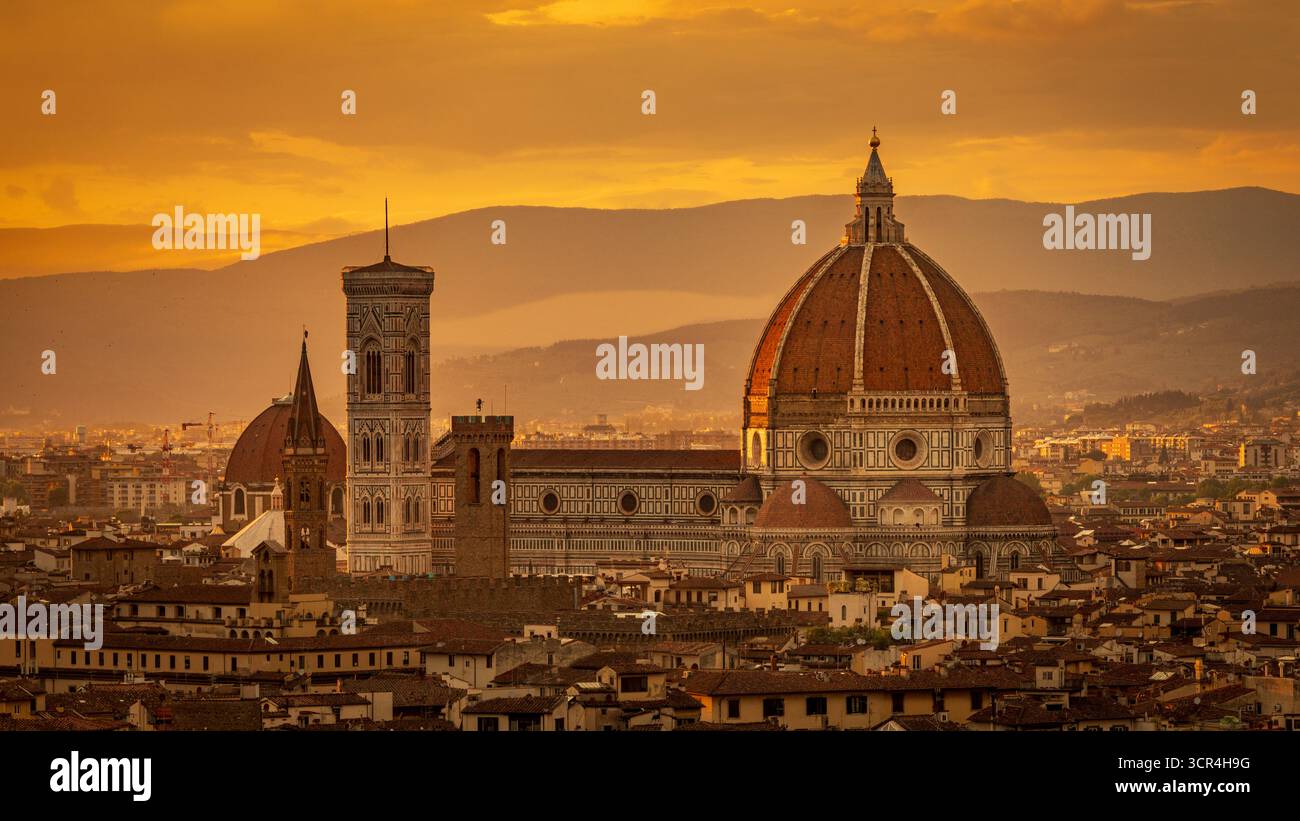 Skyline di Firenze con l'iconico Duomo, la Cattedrale di Santa Maria del Fiore, al tramonto su un cielo dorato. Firenze, Italia Foto Stock