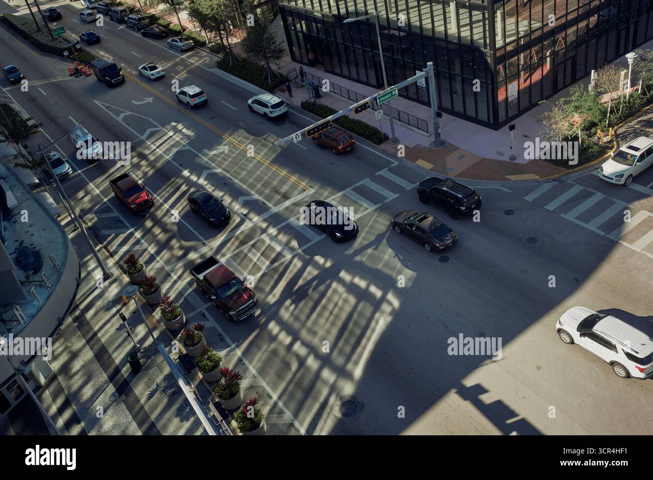 Vista aerea di un intersezione urbana trafficata con auto e ombre da un edificio in vetro. Miami, Florida, Stati Uniti Foto Stock