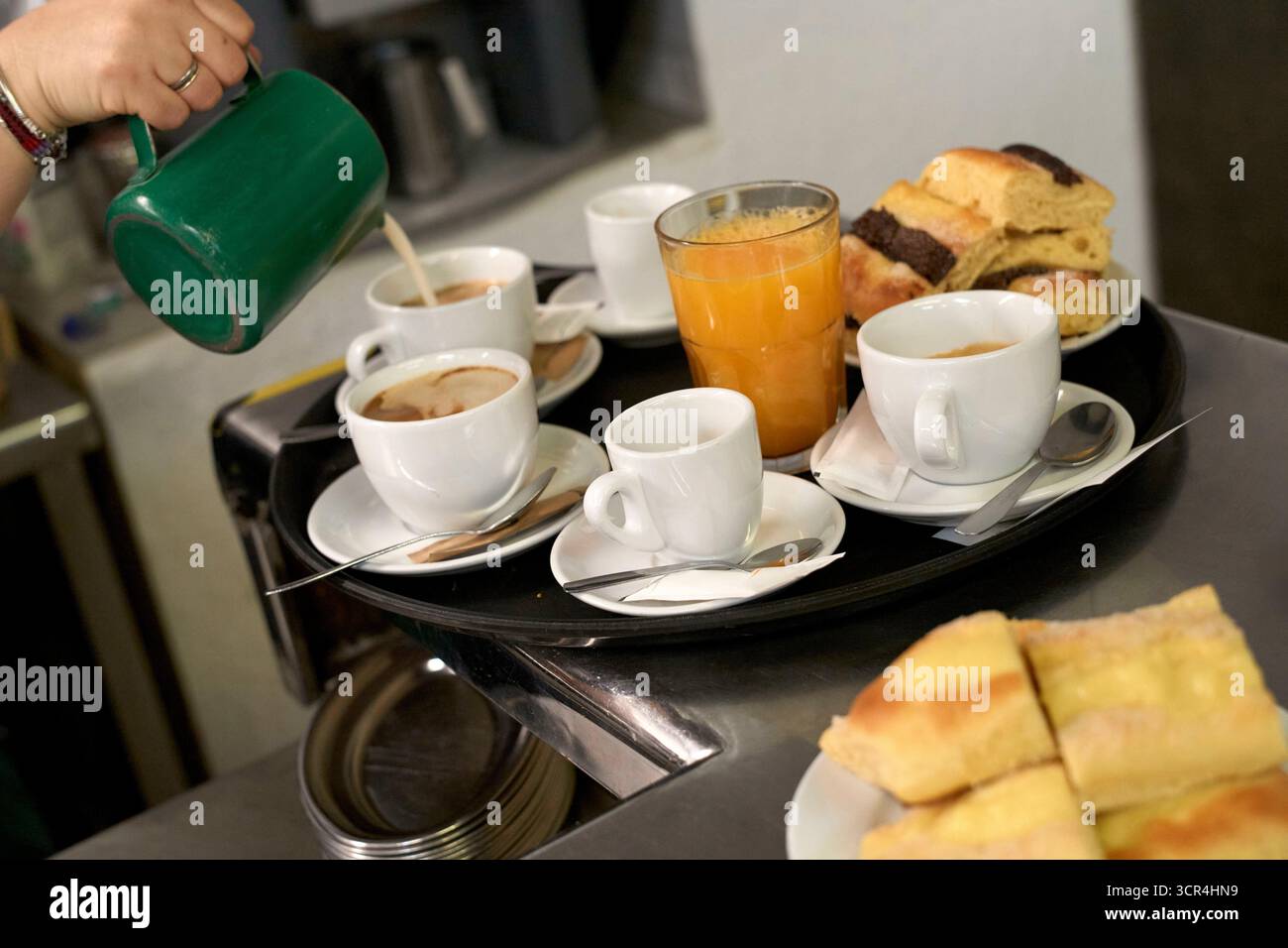 Vassoio della colazione con caffè, succo di frutta e pasticcini preparati da una tazza verde. Foto Stock