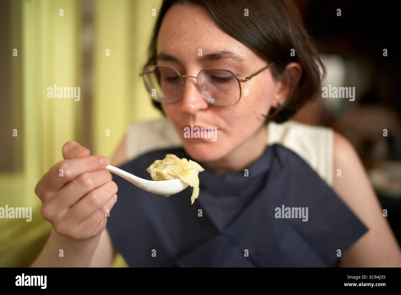 La donna ama mangiare un boccone usando un cucchiaio in un ambiente informale. Foto Stock
