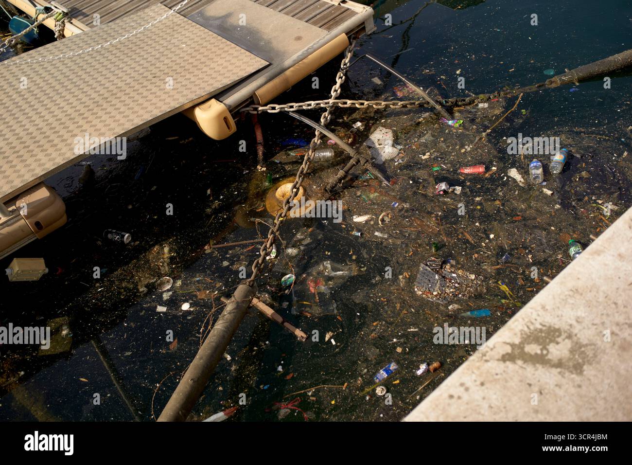 Acqua inquinata vicino a un molo con rifiuti e detriti che galleggiano sulla superficie di Marsiglia, Francia Foto Stock