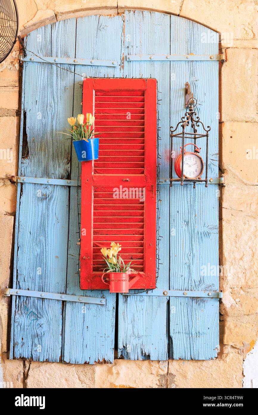 Vecchio pannello decorativo della porta con otturatore e pentole per piante. Rosso su blu. Larnaca, Cipro. Foto Stock