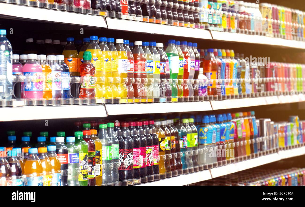 Bottiglie e lattine di bibite analcoliche sugli scaffali dei negozi, tra cui i marchi globali Coca Cola, Sprite, Dr Pepper, Lucozade, Relentless e Fanta. Bevande frizzanti. Foto Stock