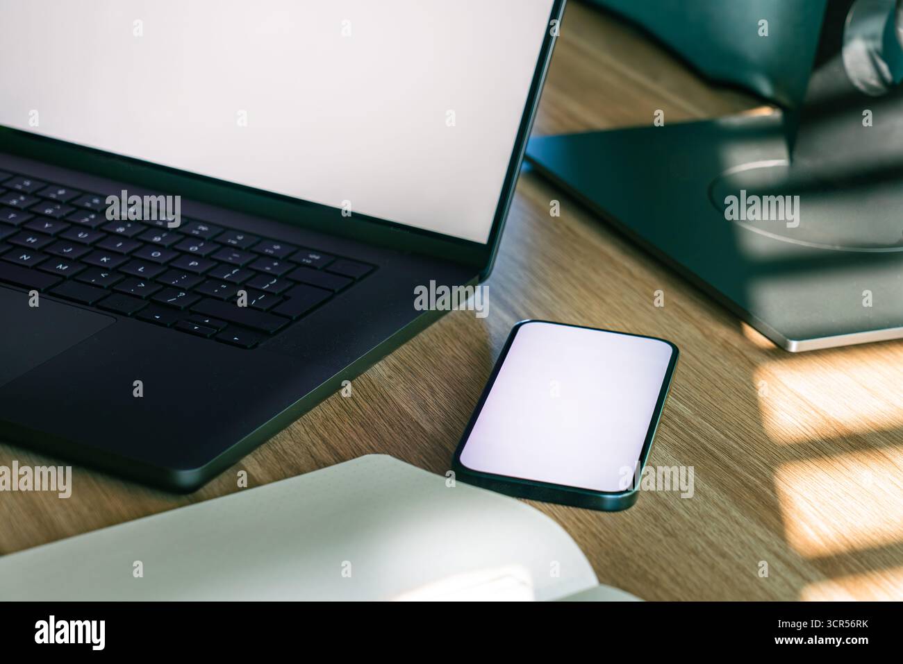 Sincronizzazione cloud con mockup dello schermo di uno smartphone laptop. Primo piano di un moderno spazio di lavoro con schermo vuoto per smartphone, ideale per il design dell'interfaccia utente delle app, il laptop aperto e le note Foto Stock