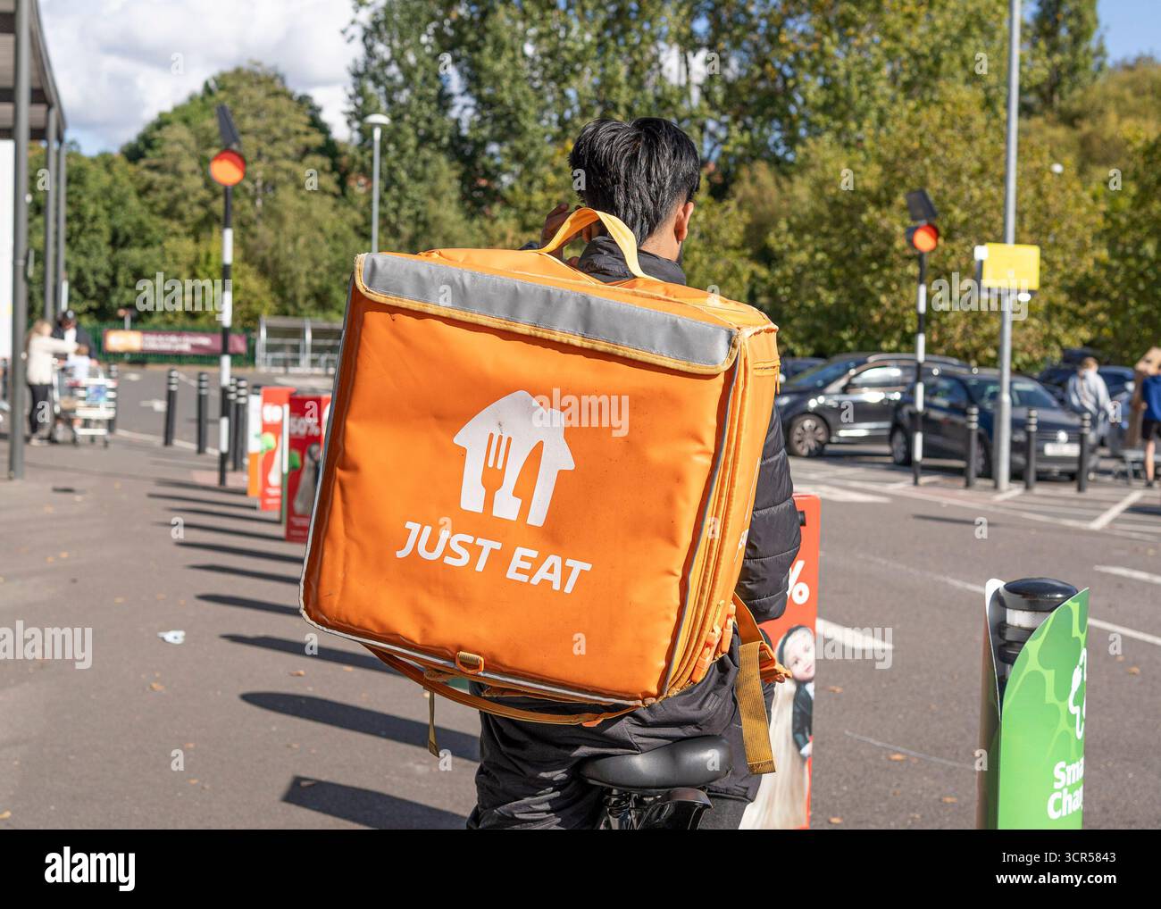 Vista posteriore di un motociclista Just Eat Delivery fuori da un supermercato Sainsbury's del Regno Unito che ha effettuato un ritiro e pronto per la consegna. Foto Stock