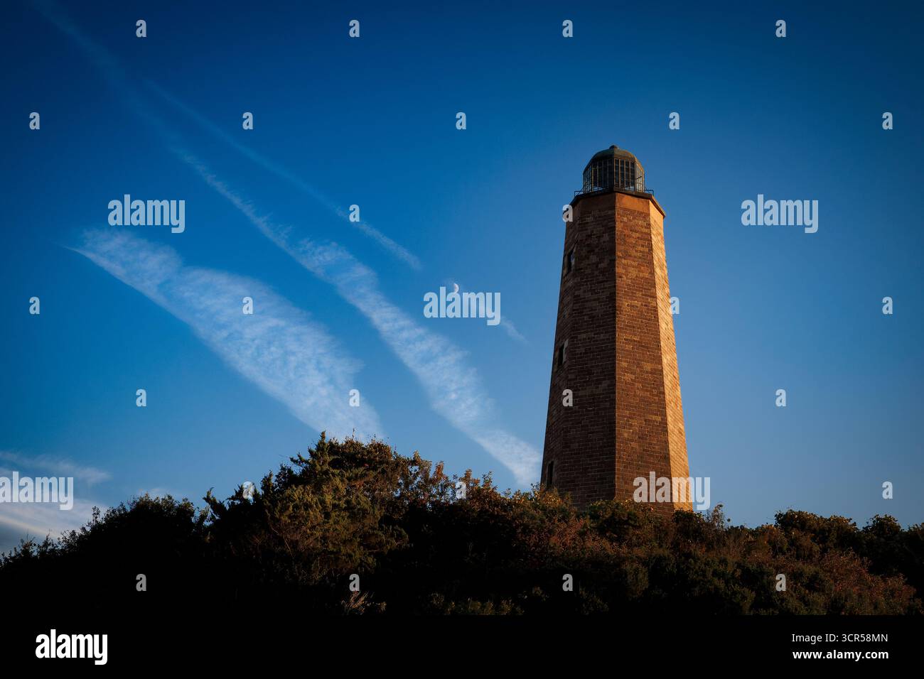 Il cielo azzurro riscalda il lato del vecchio faro di Cape Henry, costruito nel 1792, a Virginia Beach, Virginia. Foto Stock