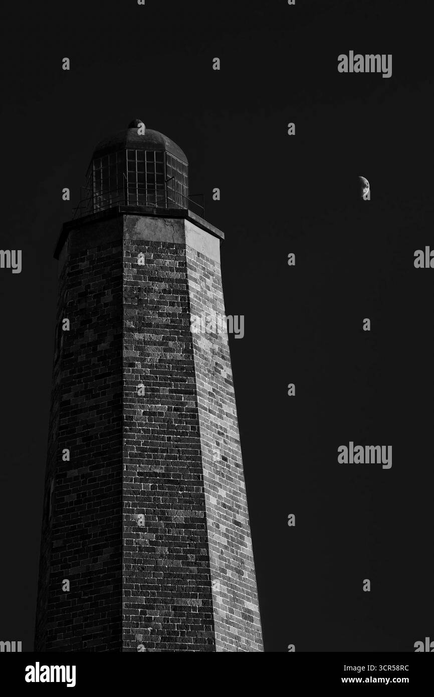 Una luna luminosa nel cielo serale dietro il vecchio faro di Cape Henry, costruito nel 1792, a Virginia Beach, Virginia. Foto Stock