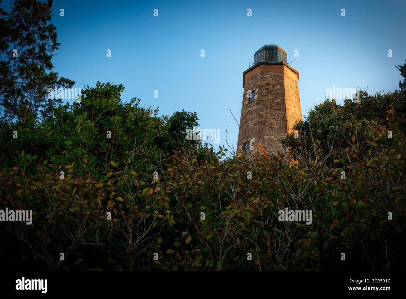 Il sole della sera sopra riscalda il lato del vecchio faro di Cape Henry, costruito nel 1792, a Virginia Beach, Virginia. Foto Stock