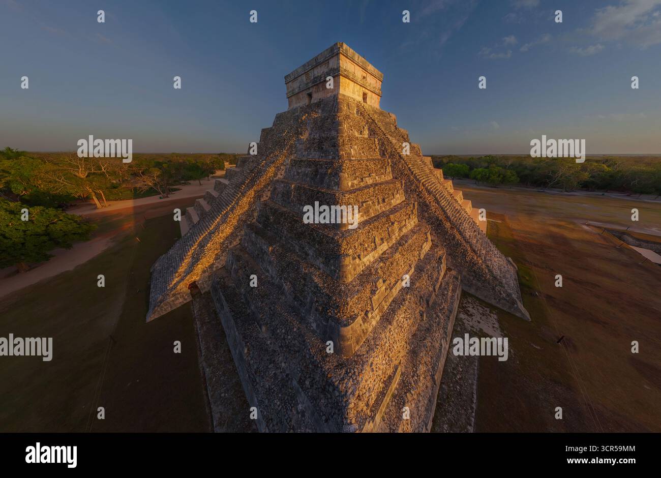 Vista aerea della maestosa piramide di Kukulkan, che sorge con antiche pietre all'orizzonte, bagnata dal caldo bagliore del sole che tramonta, Chichén Itzá, Yucatán, Messico. Foto Stock