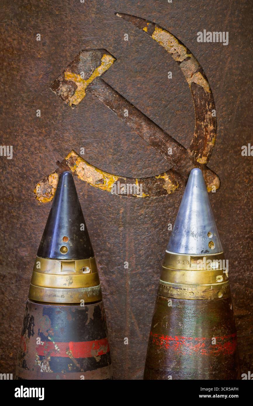 Due vecchie bombe militari di fronte a un martello e una falce sospese dell'URSS Foto Stock