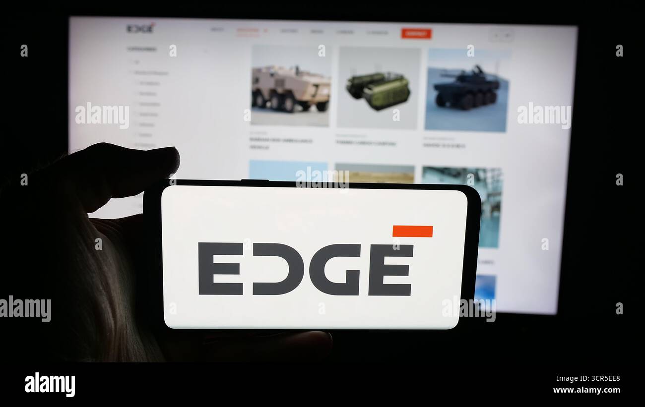 Stoccarda, Germania - 09-27-2025: Persona che detiene il cellulare con il logo della società di difesa degli Emirati Edge Group PJSC sullo schermo davanti alla pagina web. Foto Stock