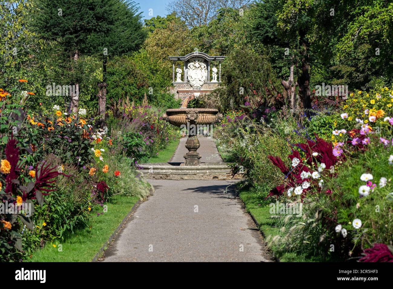 Vista verso la fontana italiana di marmo rosso di Verona tra i doppi confini del Wall Garden a Nymans, West Sussex, Inghilterra, Regno Unito. Foto Stock