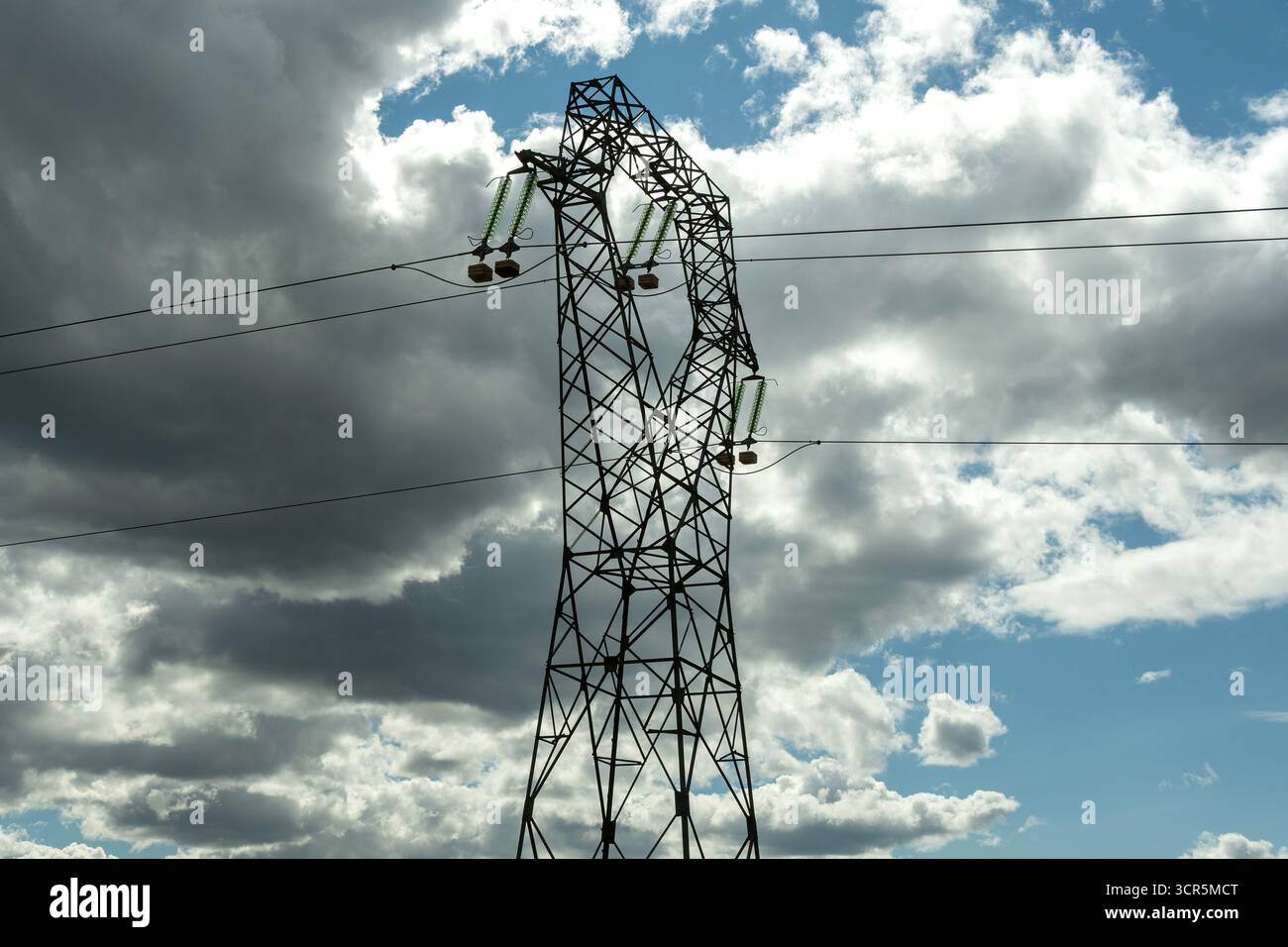 Linee elettriche ad alta tensione contro un cielo blu brillante con nuvole sparse , Puy de Dome, Alvernia Rodano Alpi, Francia Foto Stock