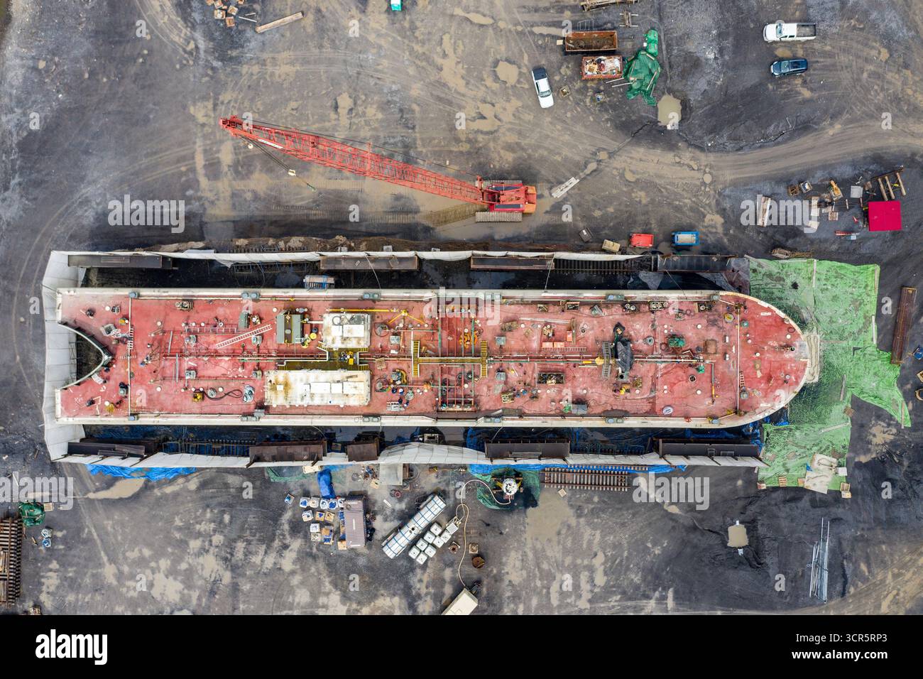La vista aerea della nave con ponte rosso si staglia fortemente contro i dintorni grigi, la gru che incombe sul ponte della nave, Hudson, New York, Stati Uniti. Foto Stock