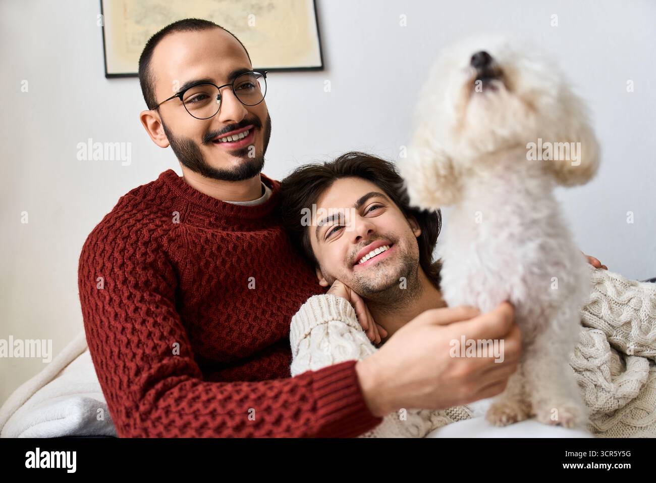 Gli uomini gioiosi condividono risate e affetto, mentre il loro cane aggiunge un fascino festoso alle case. Foto Stock
