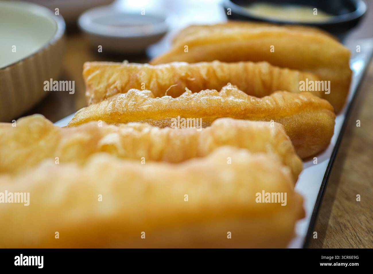 Primo piano di bastoncini di Youtiao cinesi serviti con crema pasticcera, croccante cibo di strada asiatico dorato dalla Chinatown di Bangkok. Foto Stock