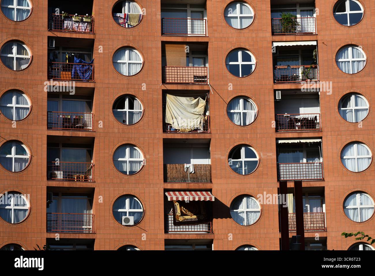 edificio di appartamenti fronteggiato in mattoni rossi con finestre circolari Foto Stock