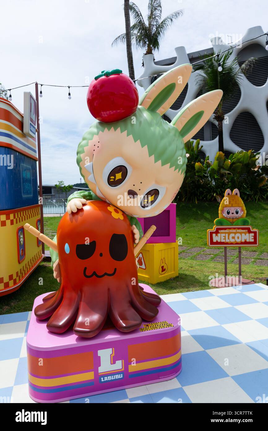 Vista verticale. Evento pop-up per il Mini Market di Labubu, zona fotografica, labubu verde sopra un polpo rosso. Singapore. Foto Stock