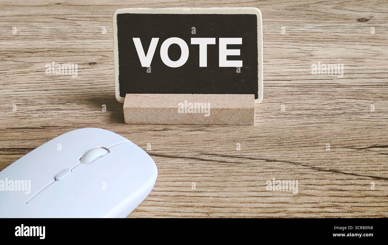 Concetto di voto online: Testo di VOTO bianco su lavagna con mouse per computer su scrivania in legno Foto Stock