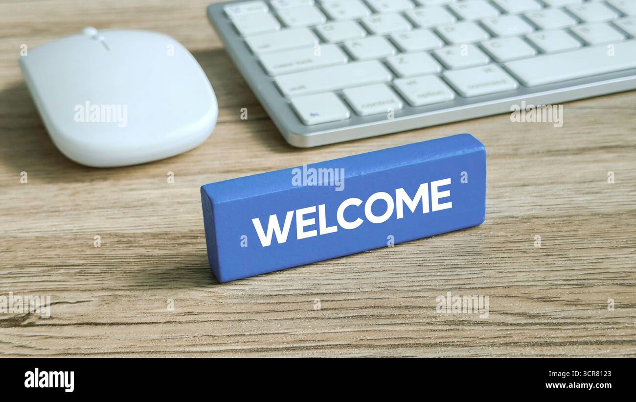 Testo DI BENVENUTO in grassetto su un blocco di legno blu che simboleggia l'ospitalità, l'onboarding o il servizio clienti Foto Stock