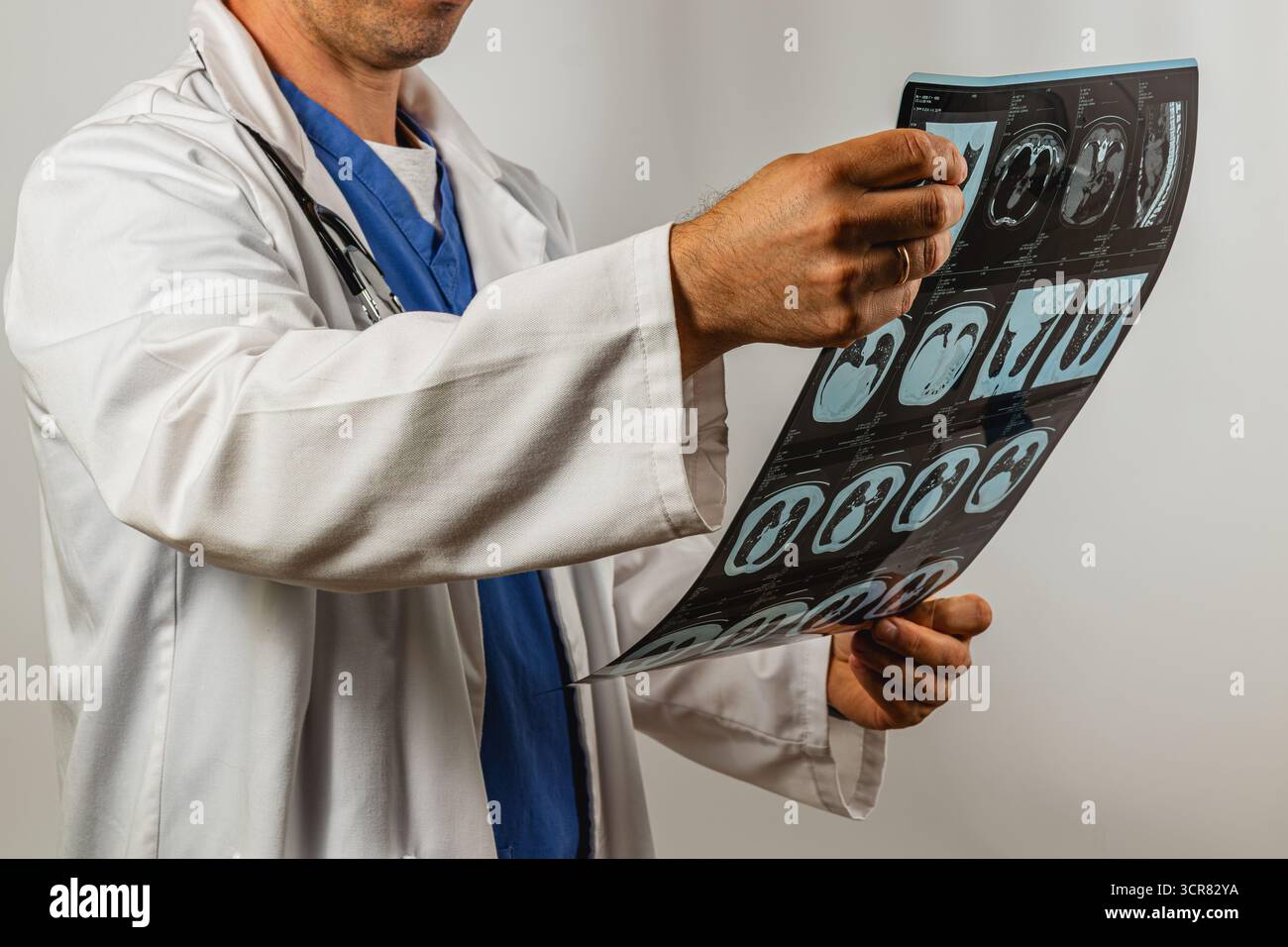 Un professionista sanitario in un camice da laboratorio esamina le immagini mediche in un ambiente clinico, dimostrando attenzione e attenzione ai dettagli durante l'analisi Foto Stock