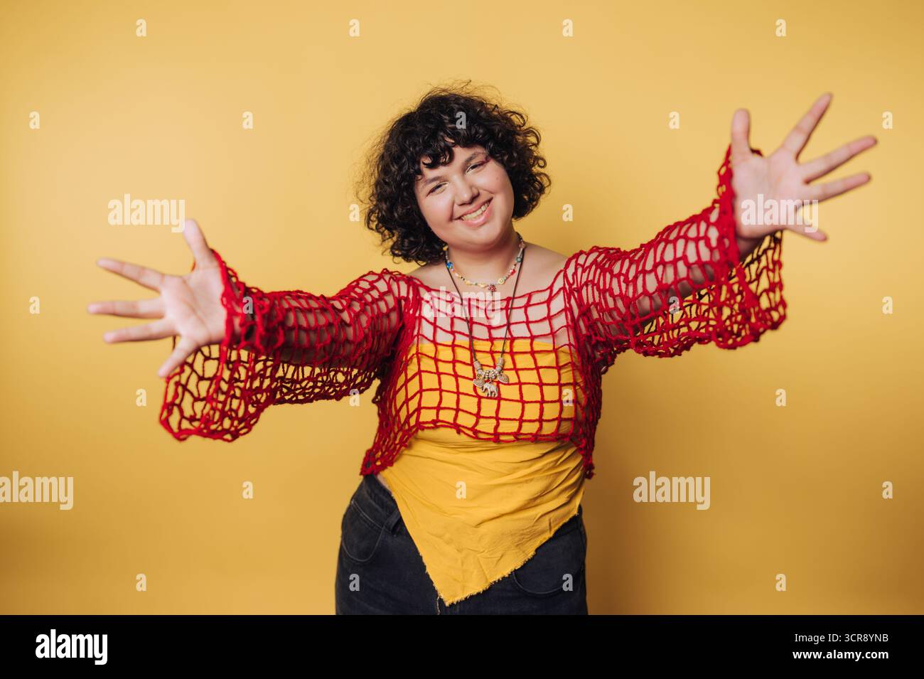 La creatività individuale mette in risalto la moda vivace in una posa giocosa ed espressiva su uno sfondo giallo brillante Foto Stock