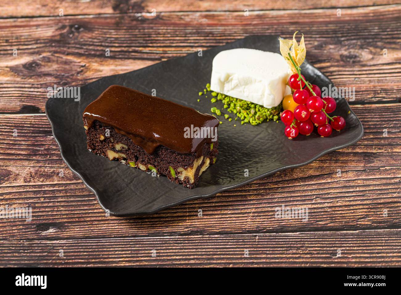 Ricco brownie al cioccolato con gelato alla vaniglia e frutti di bosco Foto Stock