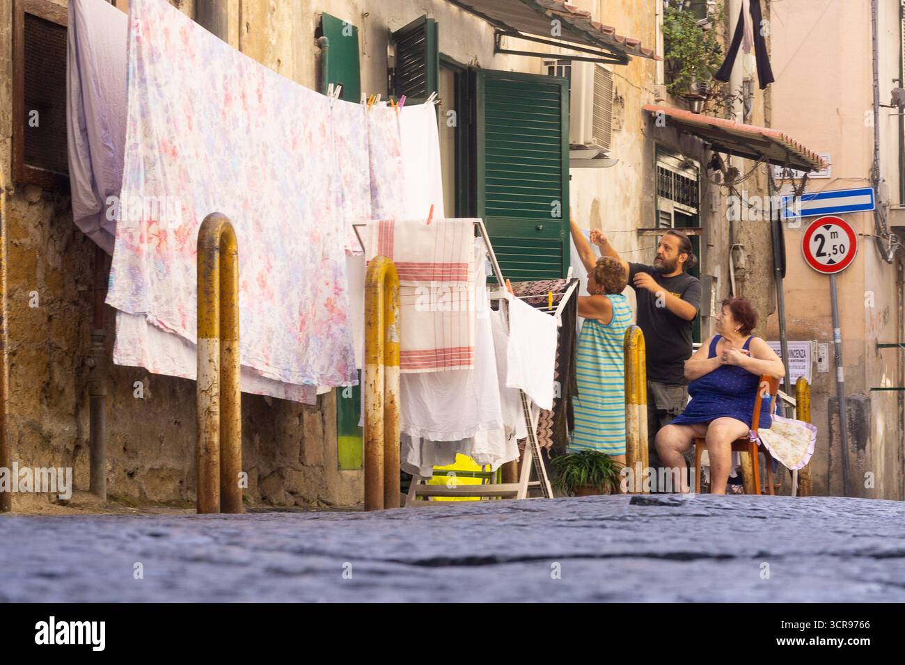 I residenti locali appendono il bucato fuori da una casa al piano terra (basso) in Via San Vincenzo nel quartiere Rione Sanità, Napoli, Italia. Foto Stock