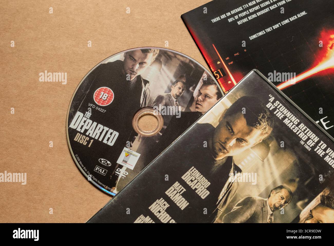 Disco DVD "The Departed" con copertina con attori principali, isolato su sfondo bianco chiaro, ripresa dall'angolo superiore Foto Stock