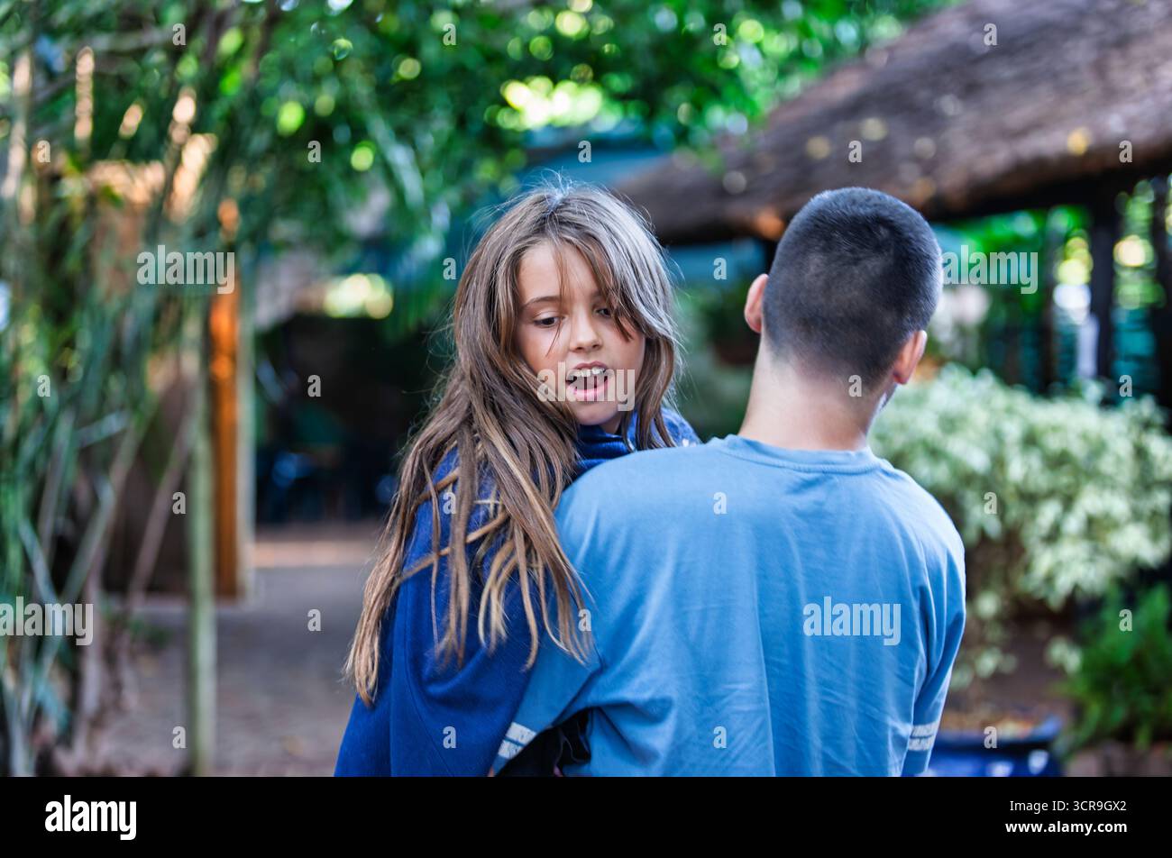 amore fraterno, bambina felice tenuta da suo fratello, testa e spalle ravvicinate, capelli lunghi e mani Foto Stock