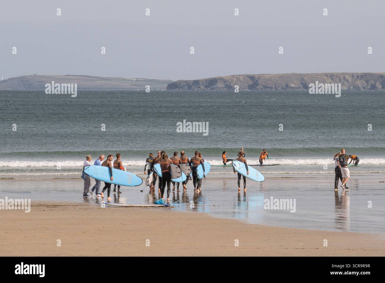 Un gruppo di vacanzieri in una lezione di surf con un istruttore della Cornish Wave Surf School presso Towan Beach a Newquay, in Cornovaglia, in Inghilterra Foto Stock