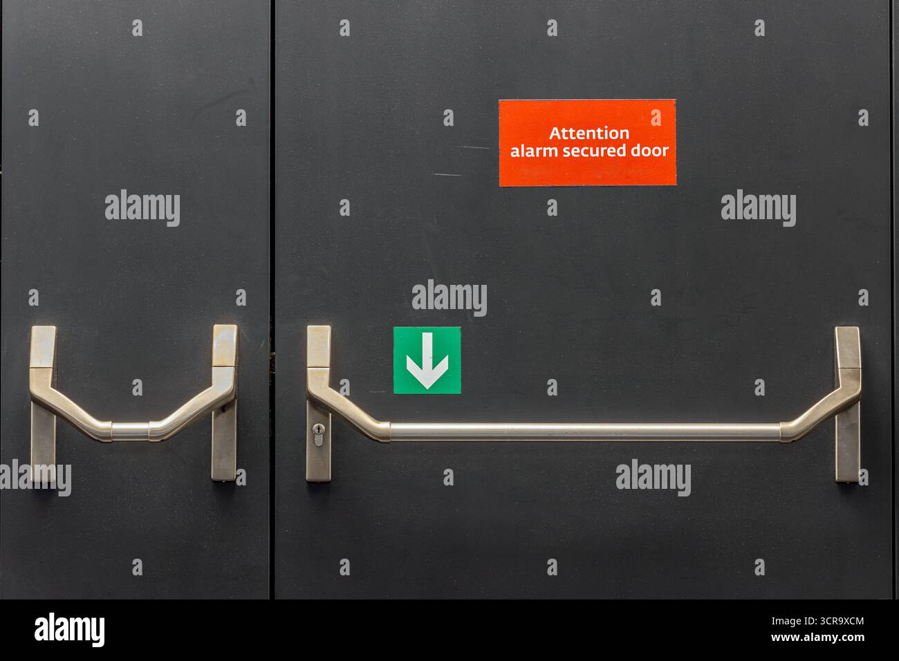 Porta di uscita di emergenza in metallo con maniglia e segnali di avvertenza e di direzione per l'apertura Foto Stock