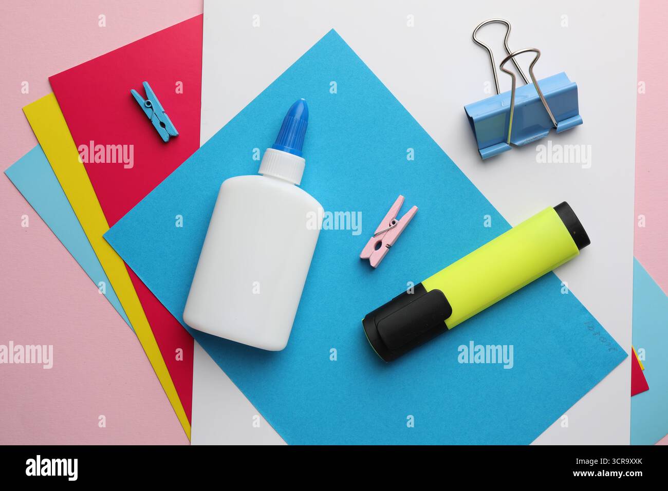 Incollare in flacone, carta colorata e altri articoli di cancelleria su sfondo rosa, piano Foto Stock