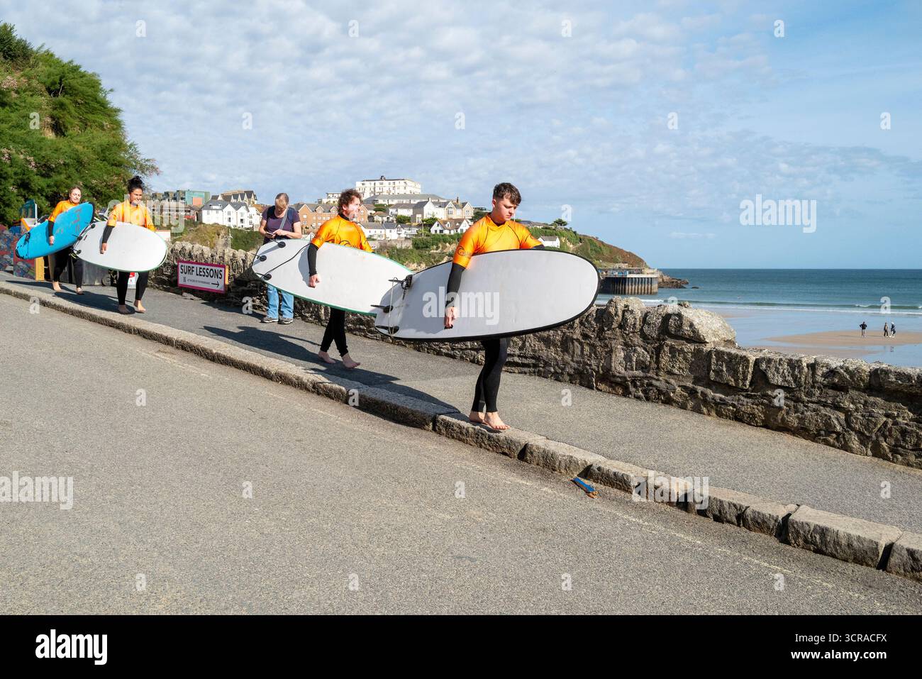Un gruppo di surfisti principianti che portano le loro tavole da surf fino a una lezione di surf a Towan Beach a Newquay, in Cornovaglia, in Inghilterra, nel Regno Unito. Foto Stock
