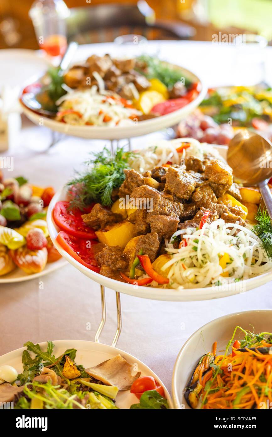 Carne salata con patate e verdure in un recipiente bianco. Perfetto per feste, banchetti o temi fotografici. Foto Stock