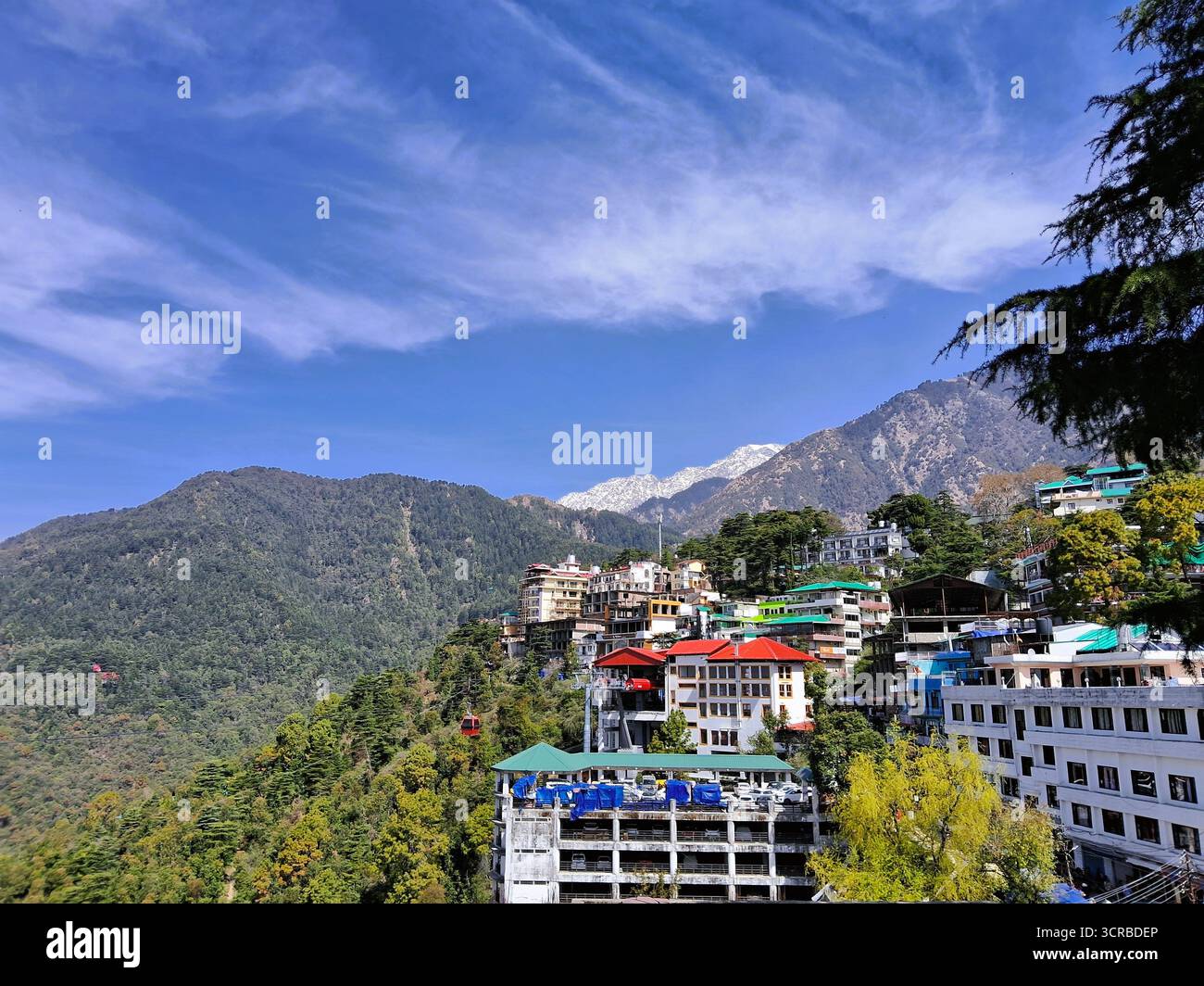 Splendida vista panoramica della città di McLeod Ganj dal complesso del Tempio Dalai Lama a Dharamshala, Himachal Pradesh, India. Si affaccia sulle maestose montagne Foto Stock